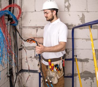 Electrician working near the Board with wires. Installation and connection of electrics.